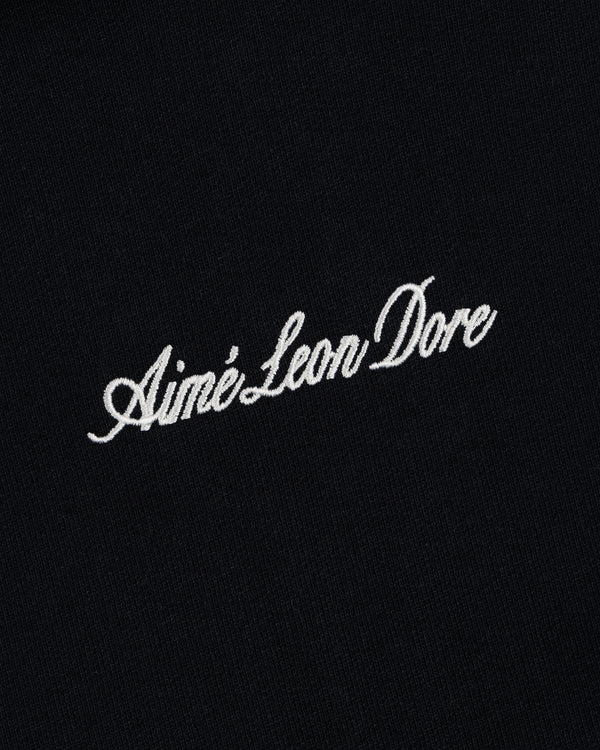 Embroidered Logo Hoodie in black with "Aimé Leon Dore" in white cursive across the center.