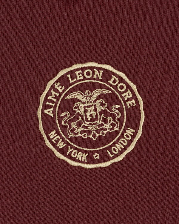 Beige embroidered Aimé Leon Dore crest with New York and London on maroon Signet Logo Hoodie.