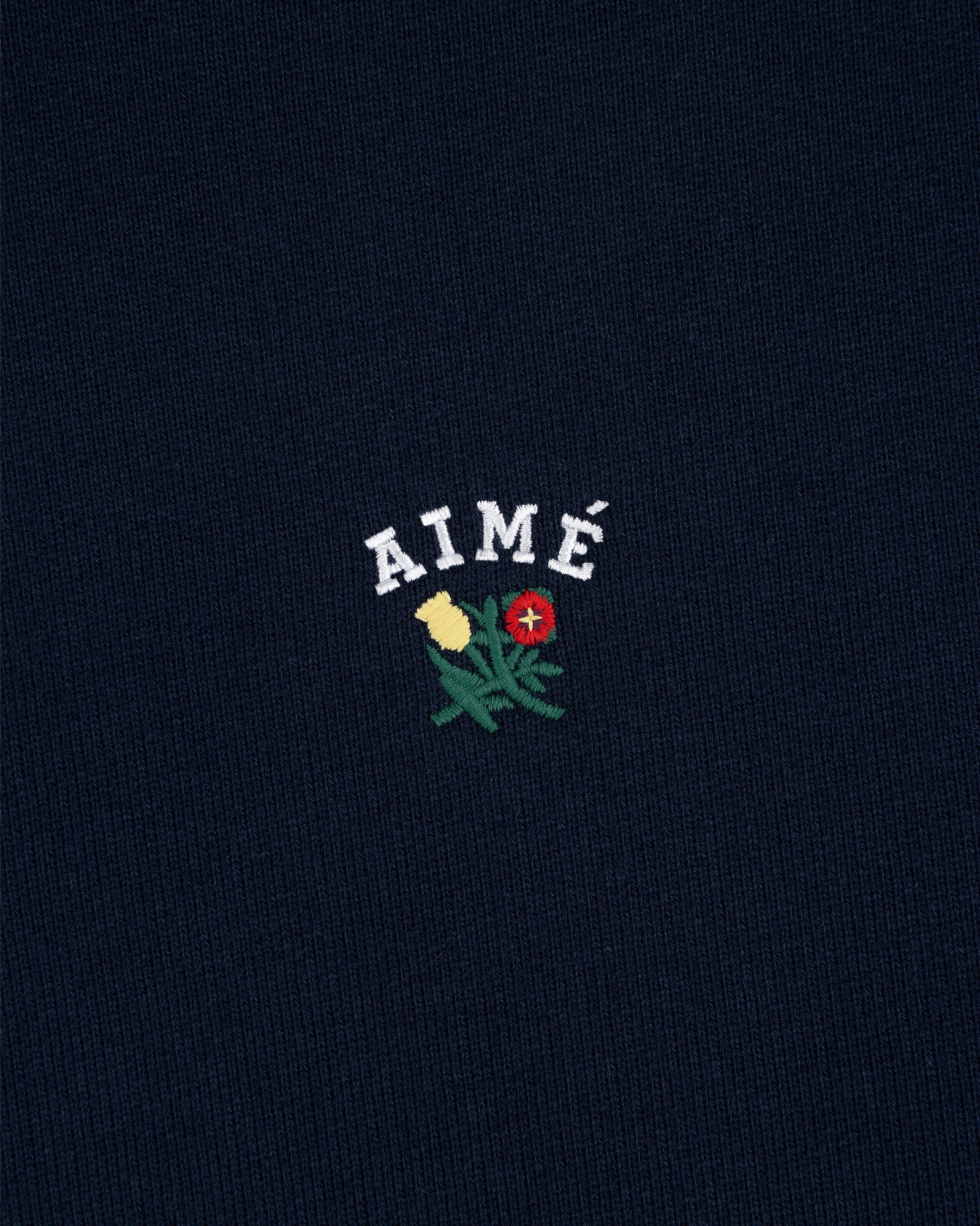 Navy Crest Hoodie featuring AIMÉ in white above yellow and red embroidered flowers with green leaves.