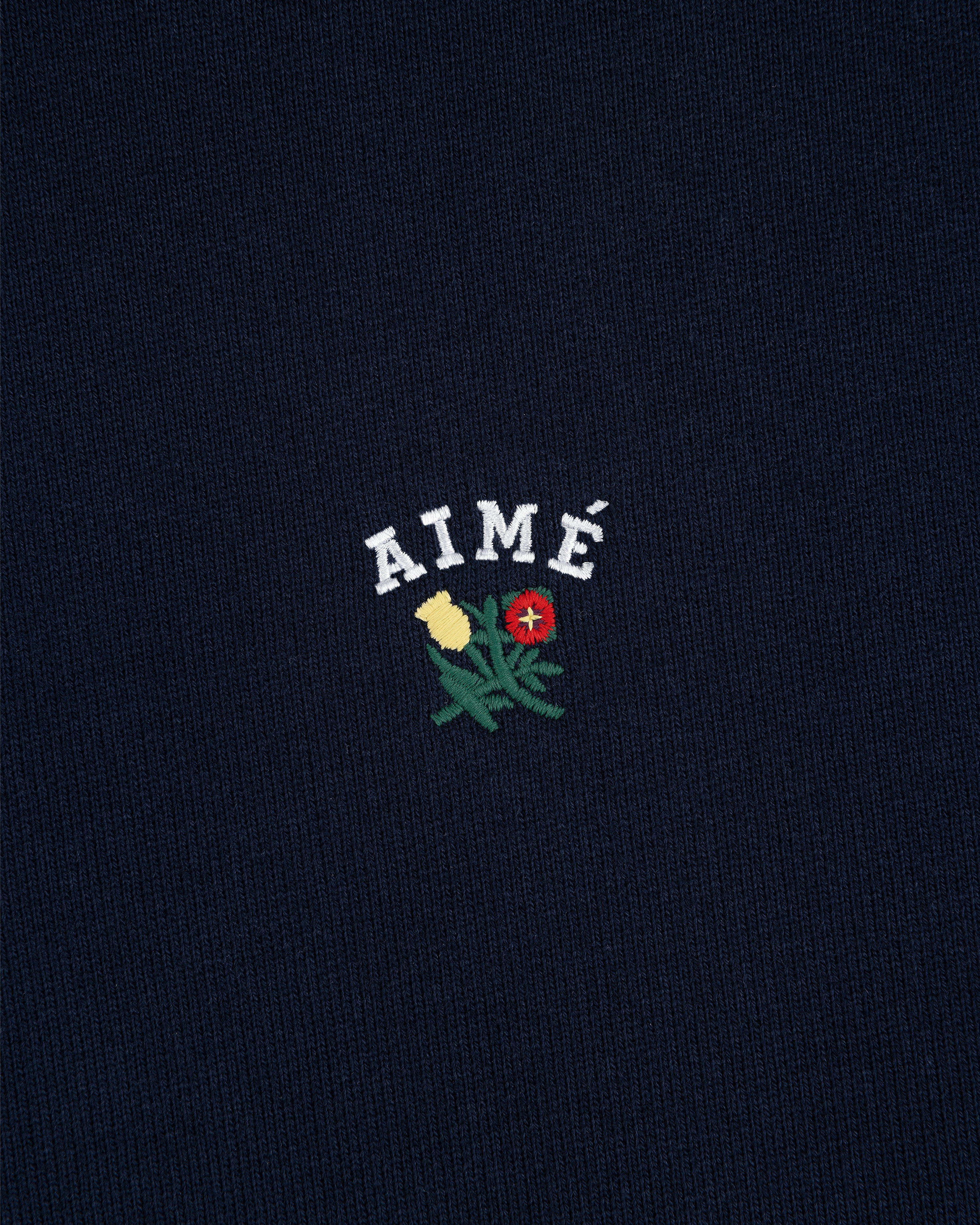 Navy Crest Hoodie featuring AIMÉ in white above yellow and red embroidered flowers with green leaves.