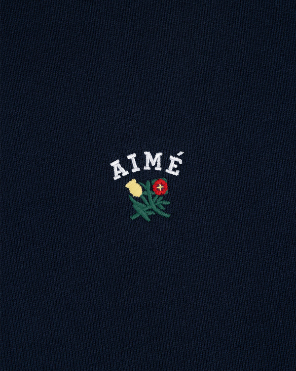Navy Crest Hoodie featuring AIMÉ in white above yellow and red embroidered flowers with green leaves.