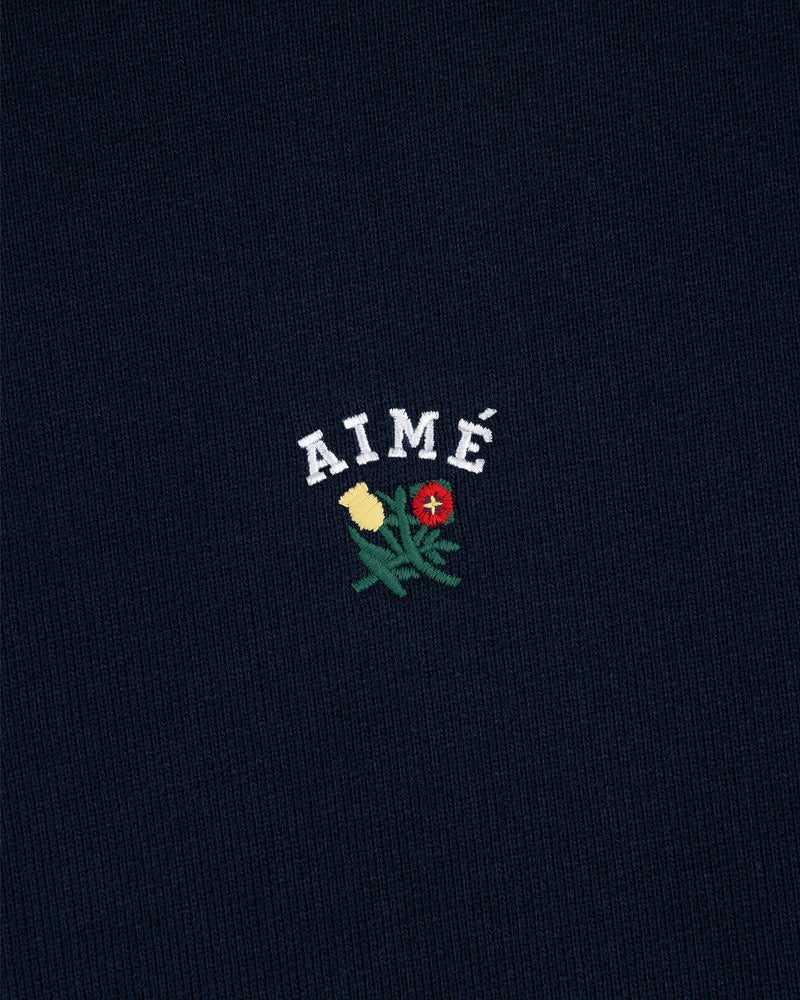 Navy Crest Hoodie featuring AIMÉ in white above yellow and red embroidered flowers with green leaves.