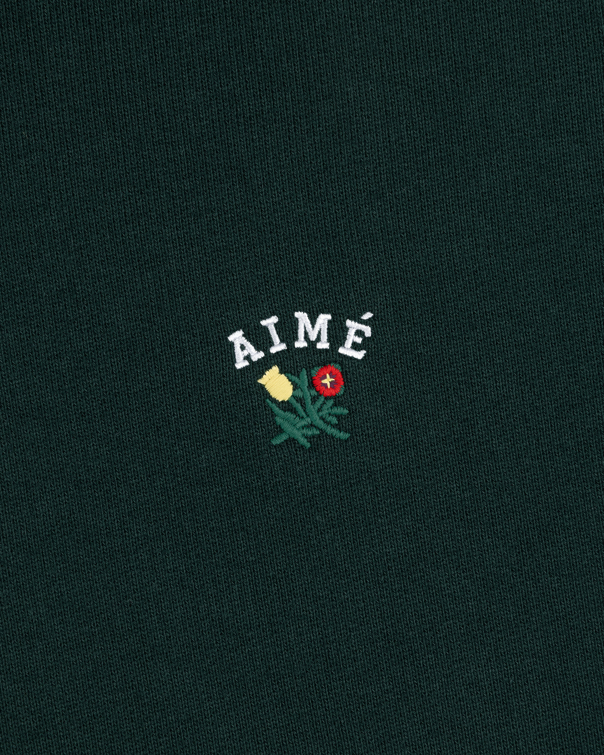 Green Crest Hoodie with AIMÉ embroidered above yellow and red flowers with green leaves.