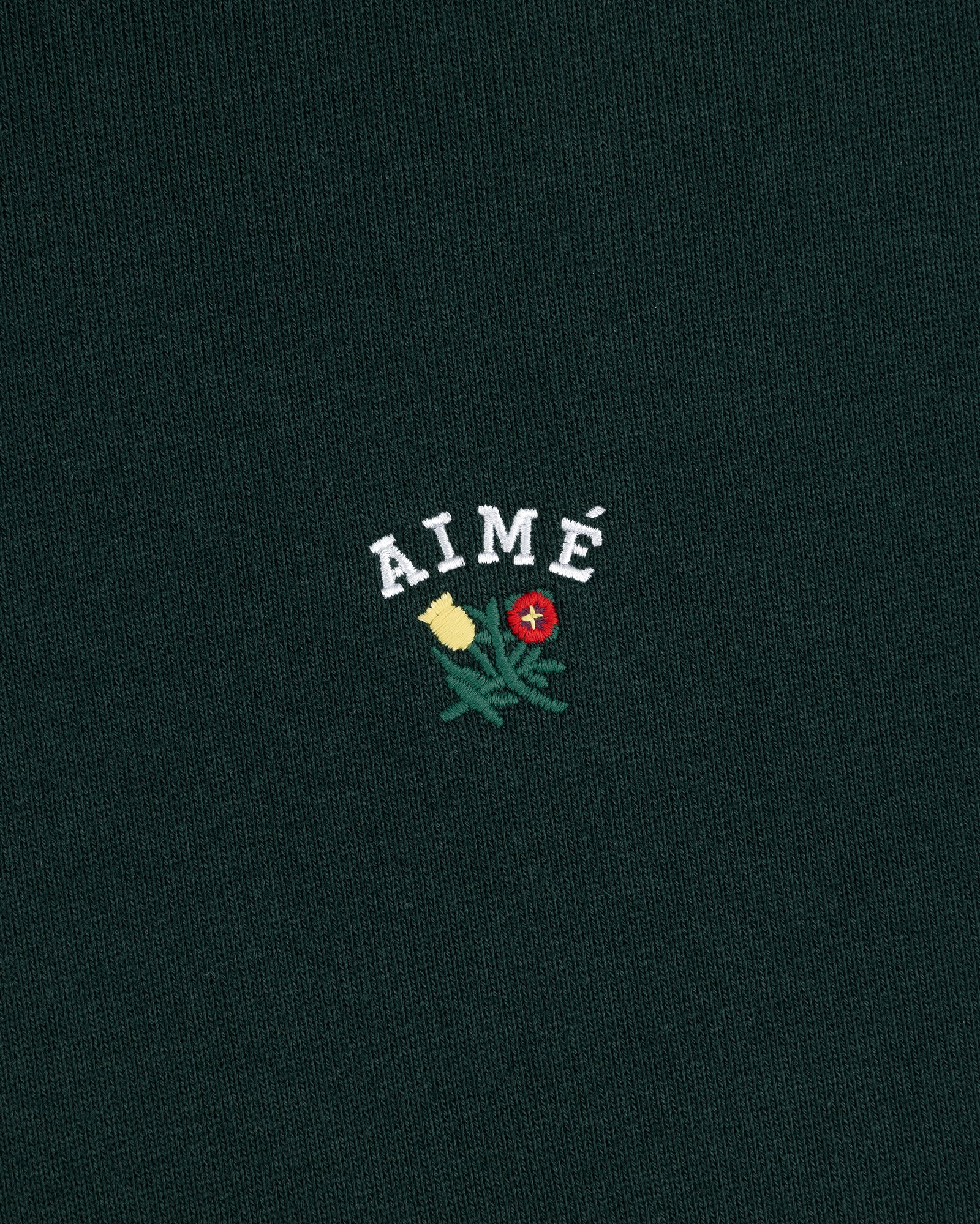 Green Crest Hoodie with AIMÉ embroidered above yellow and red flowers with green leaves.