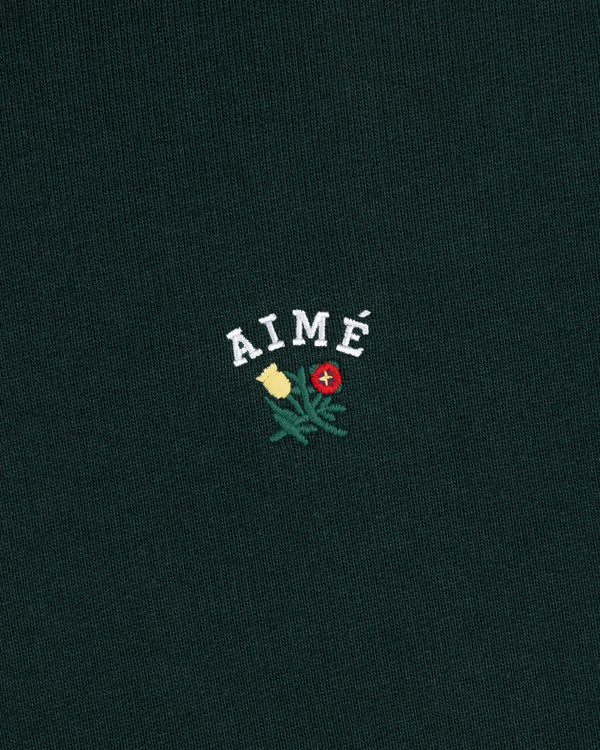 Green Crest Hoodie with AIMÉ embroidered above yellow and red flowers with green leaves.