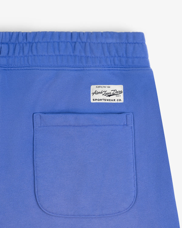 Close-up of Sun Faded Sweatpants in blue with an elastic waistband, small pocket, and white Aimé Leon Dore Sportswear Co. label.