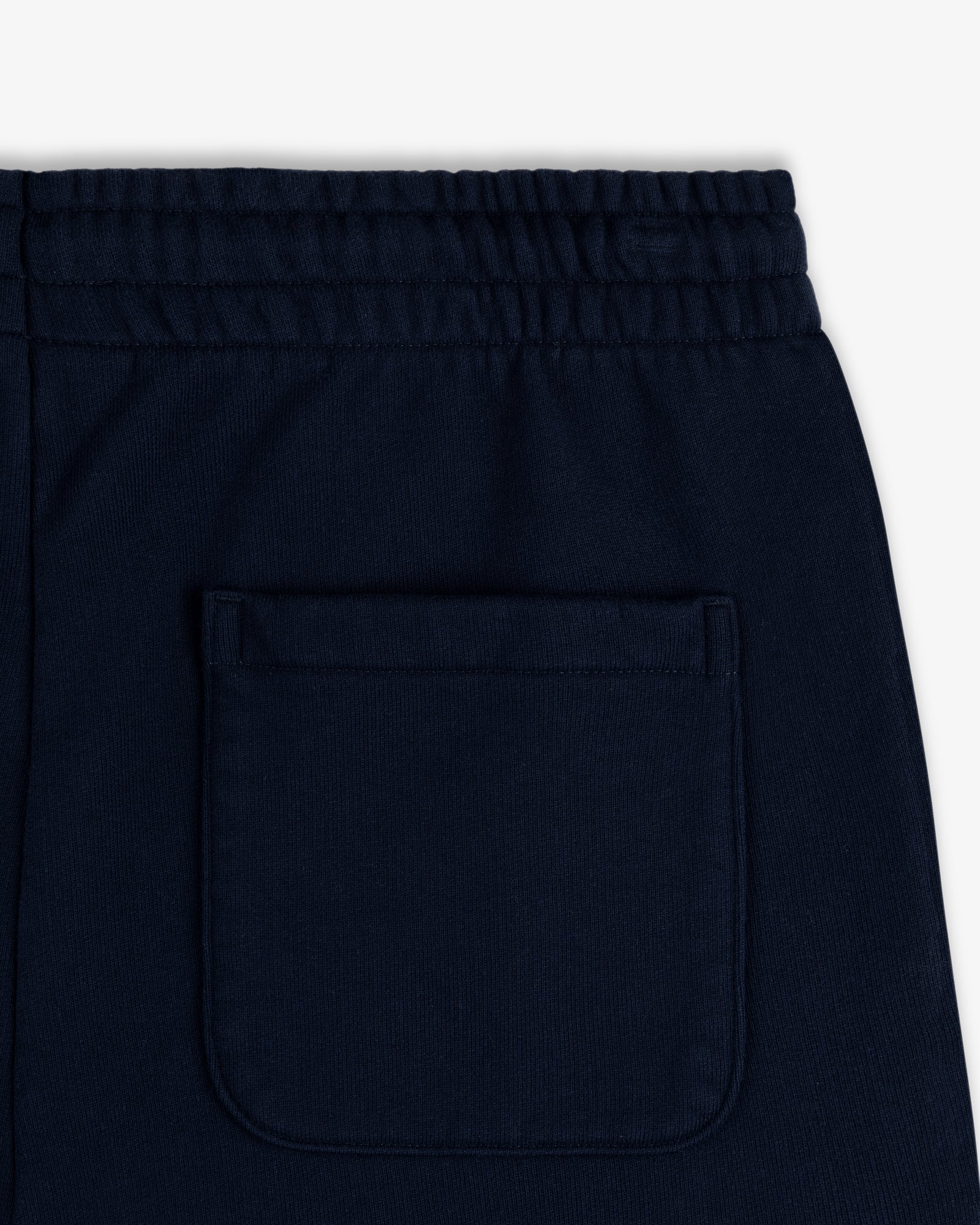 Close-up of the back waistband and pocket of Crest Sweatpants in dark navy blue with an elastic waistband.