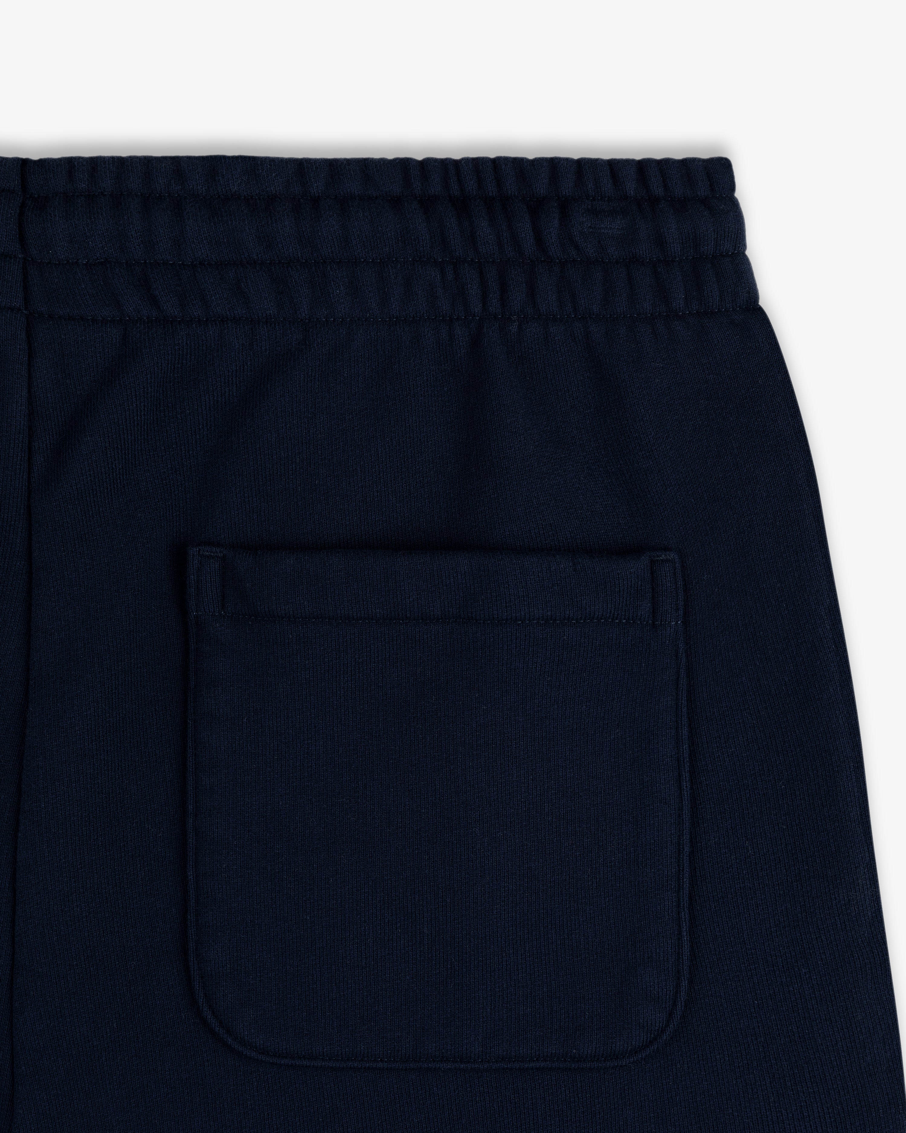 Close-up of the back waistband and pocket of Crest Sweatpants in dark navy blue with an elastic waistband.