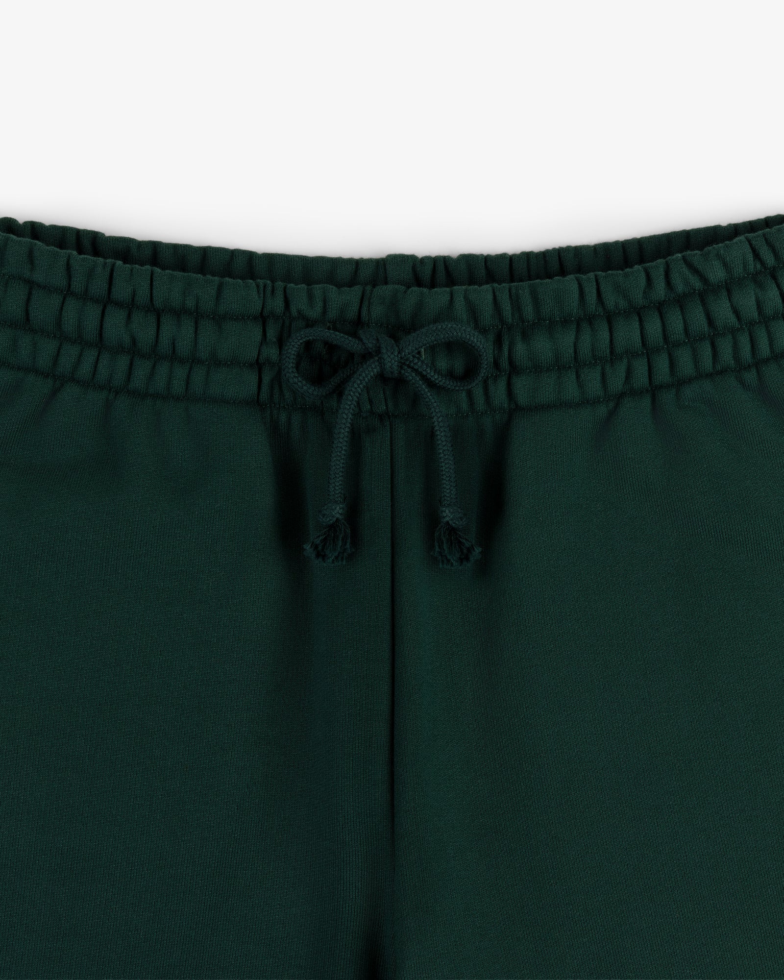 Close-up of the elastic waistband and drawstring bow on Crest Sweatpants in dark green.