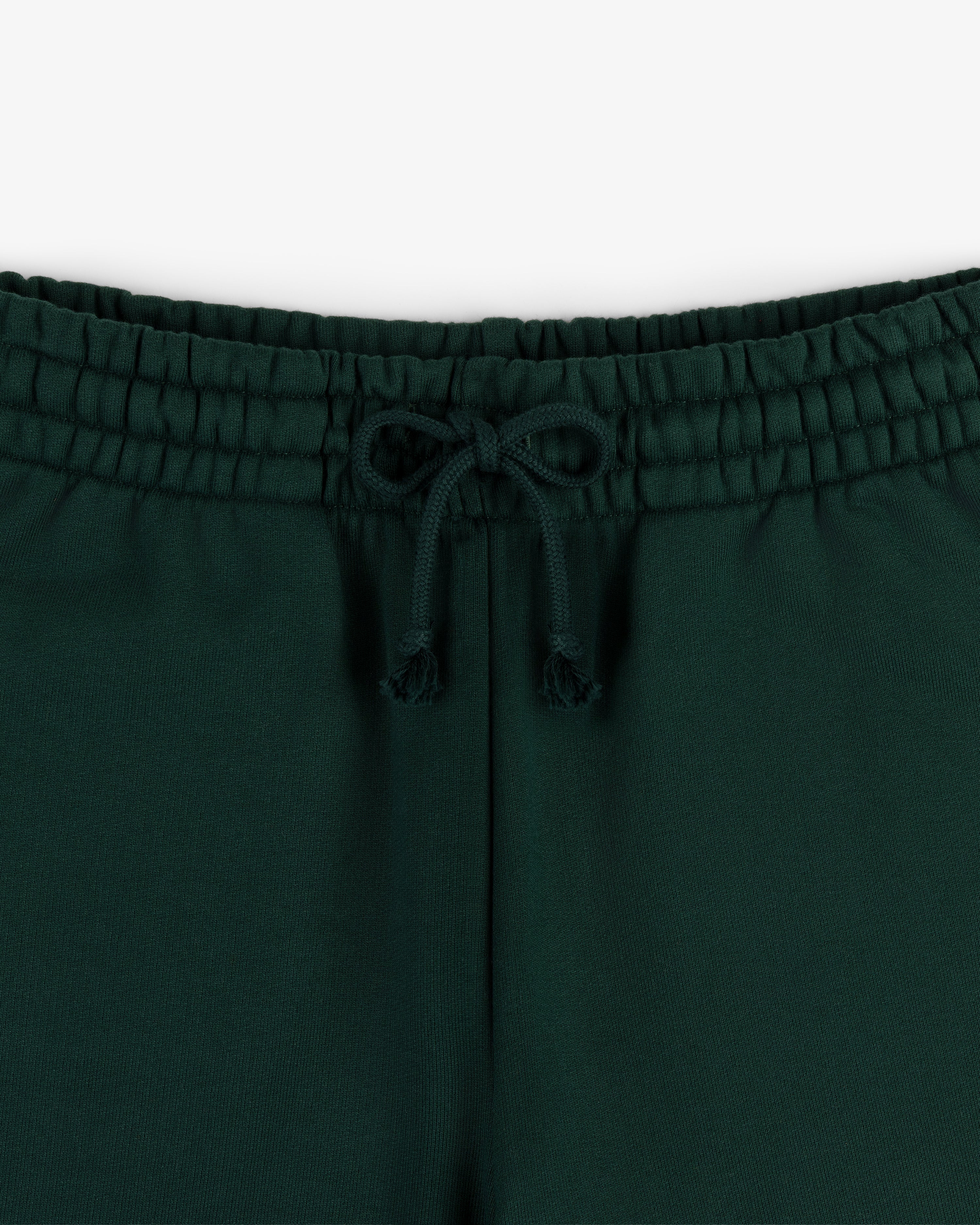 Close-up of the elastic waistband and drawstring bow on Crest Sweatpants in dark green.