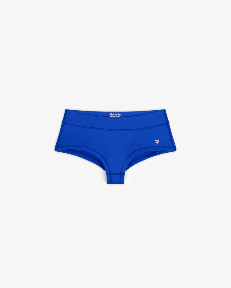 Crest Swim Short in bright blue, women's boyshort style, laid flat showing small left-hip logo on white background.