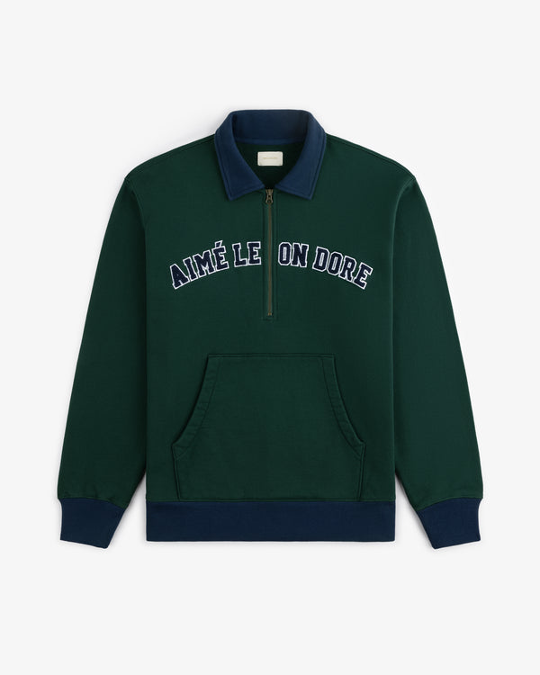 Collegiate Quarter Zip Pullover in dark green with navy collar, cuffs, and AIMÉ LEON DORE text across the chest.