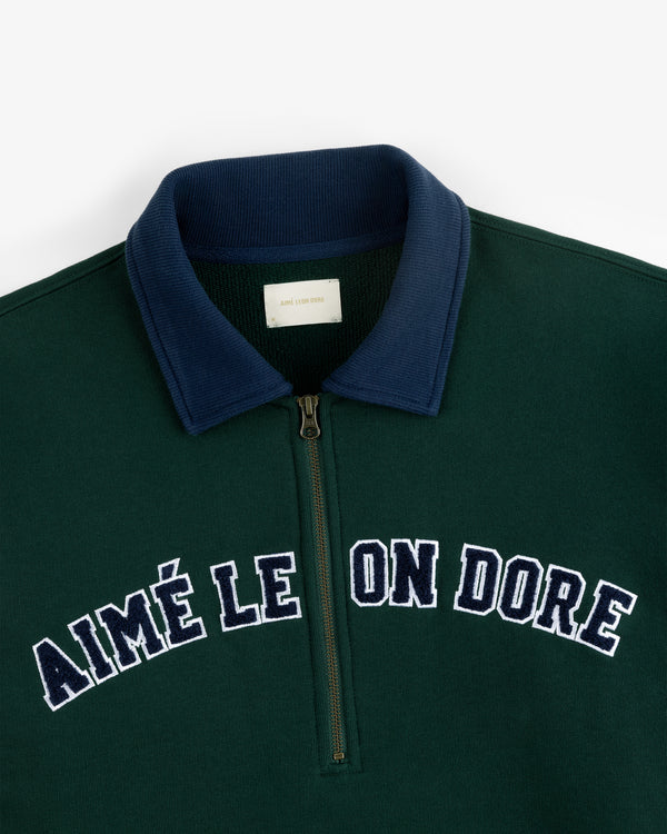 Collegiate Quarter Zip Pullover in green with a navy collar and white AIMÉ LEON DORE chest embroidery.