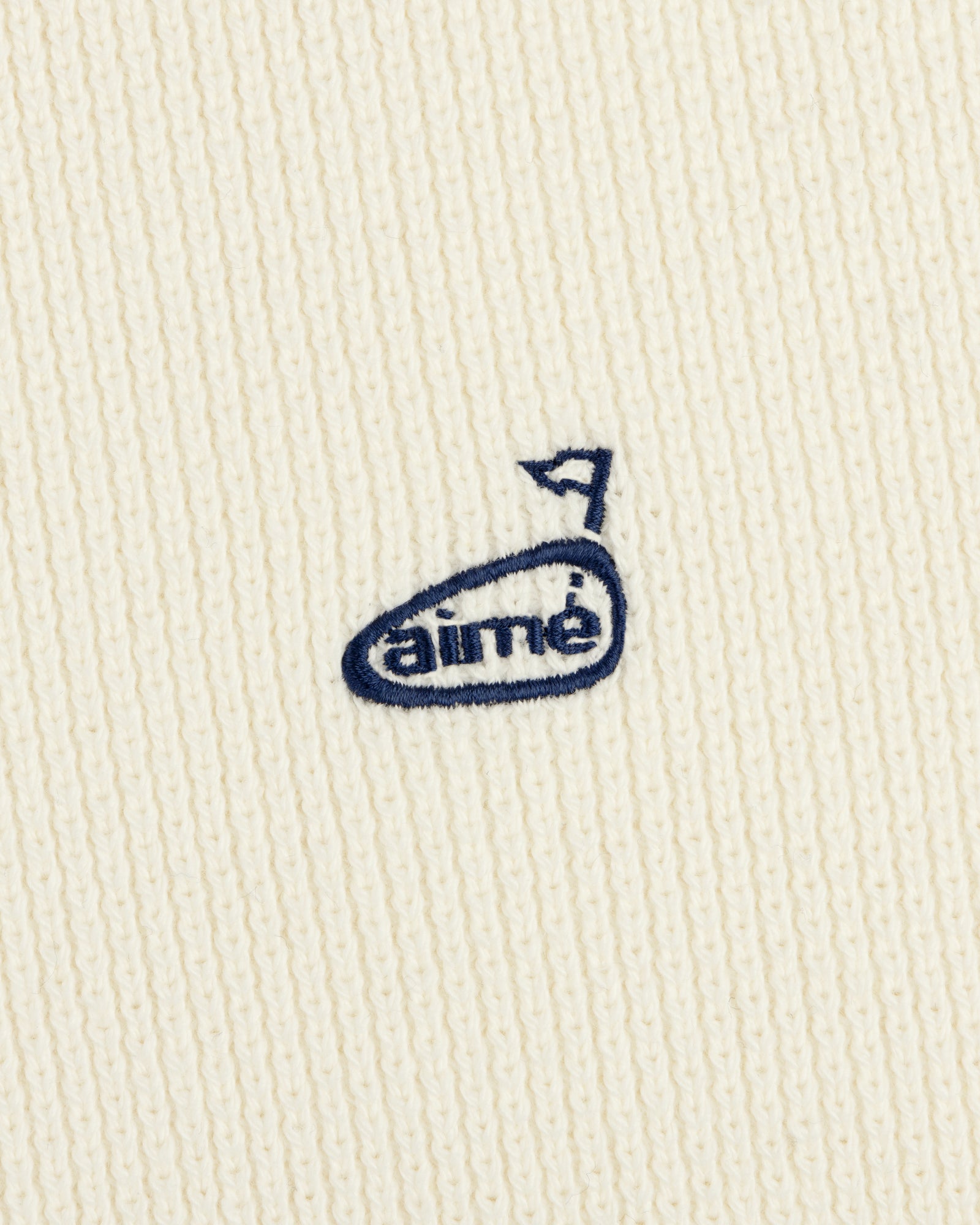 The ALD Golf Piqué Full Zip Sweater features white ribbed fabric and a small blue embroidered aimé logo with an arrow above the "e".
