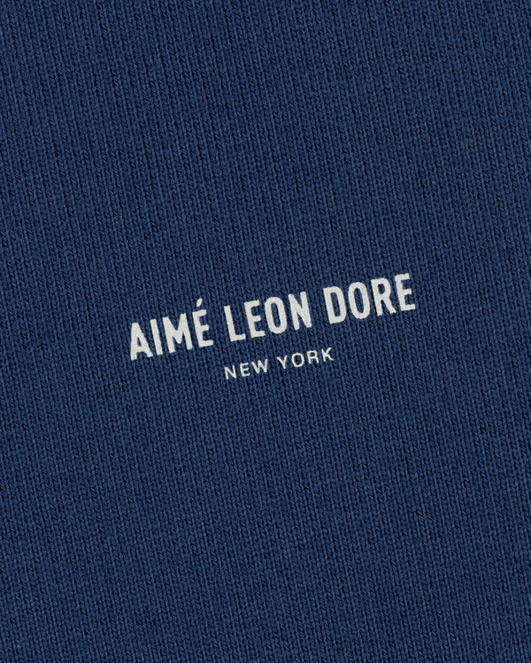 Close-up of a blue Safari Crewneck Sweatshirt with AIMÉ LEON DORE NEW YORK printed in white uppercase letters.