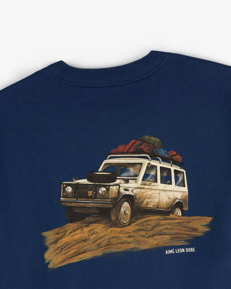 Safari Crewneck Sweatshirt in navy featuring a graphic loaded off-road vehicle and Aimé Leon Dore text underneath.