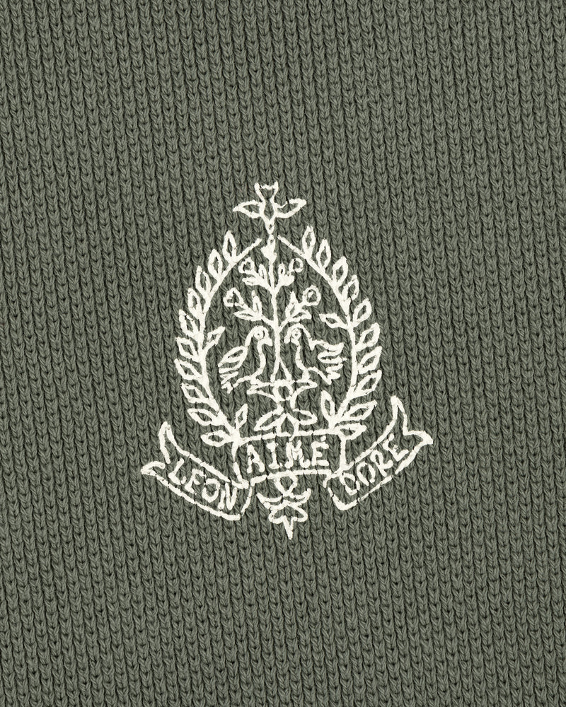 Embroidered white crest with birds, leaves, and AIME LEON DORE text on olive Saint George Piqué Crewneck Sweatshirt.
