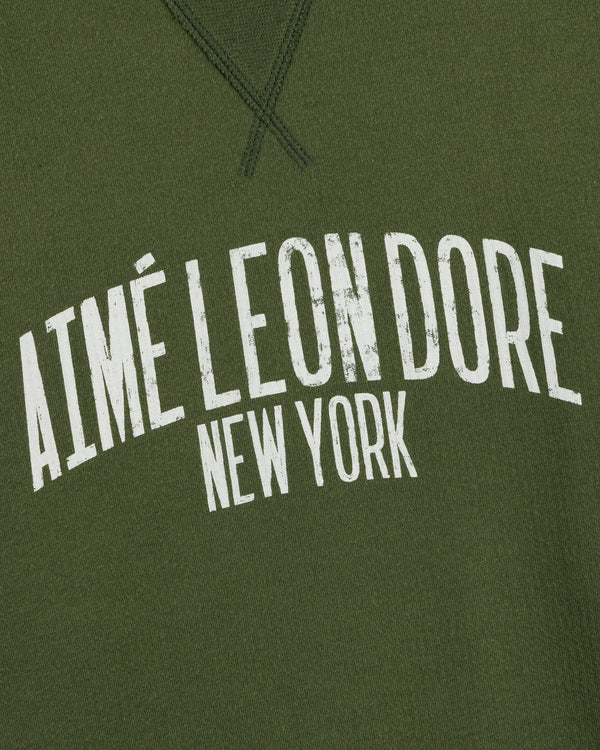 Olive green Vintage Washed Crewneck Sweatshirt with curved, distressed white AIMÉ LEON DORE NEW YORK text.
