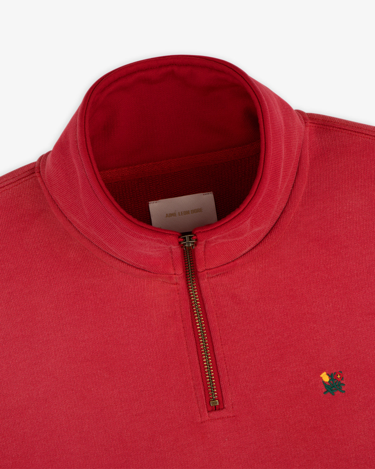 Sun Faded Crest Quarter Zip in red with small embroidered flower logo on left chest and visible zipper.