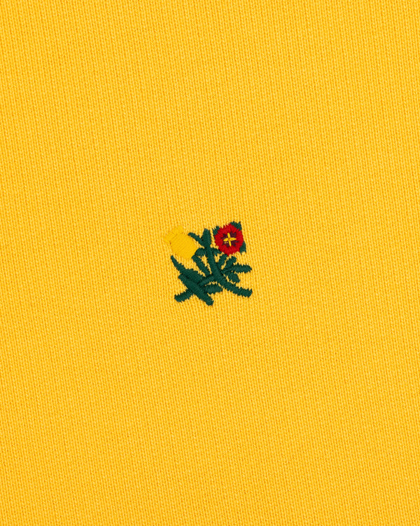 Small red and yellow embroidered flowers with green stems on the Sun Faded Crest Quarter Zip's yellow textured fabric.