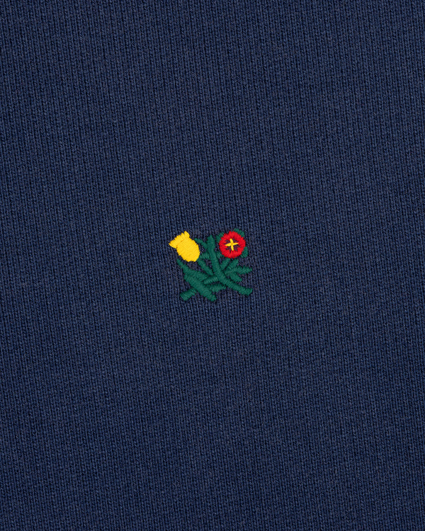 Small embroidered yellow and red flowers on dark blue Sun Faded Crest Quarter Zip with green stems.