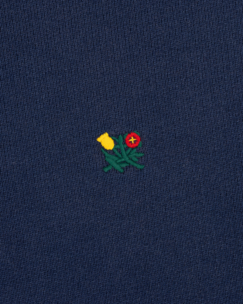 Small embroidered yellow and red flowers on dark blue Sun Faded Crest Quarter Zip with green stems.