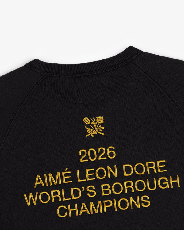 Black crewneck with yellow 2026 AIMÉ LEON DORE WORLDS BOROUGH CHAMPIONS embroidery and floral crest above.