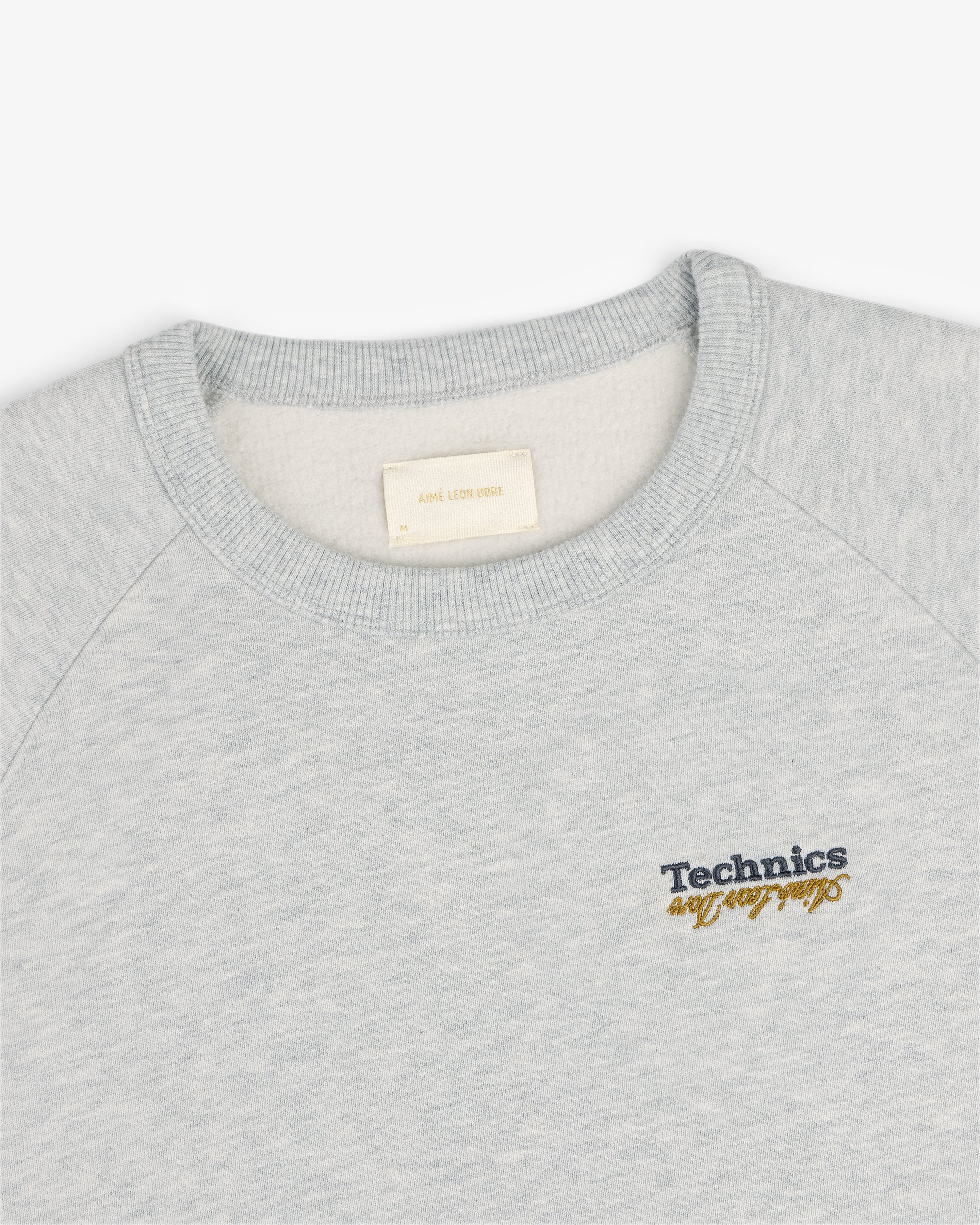 Light gray ALD / Technics World Champions crewneck with yellow script embroidered on the left chest.