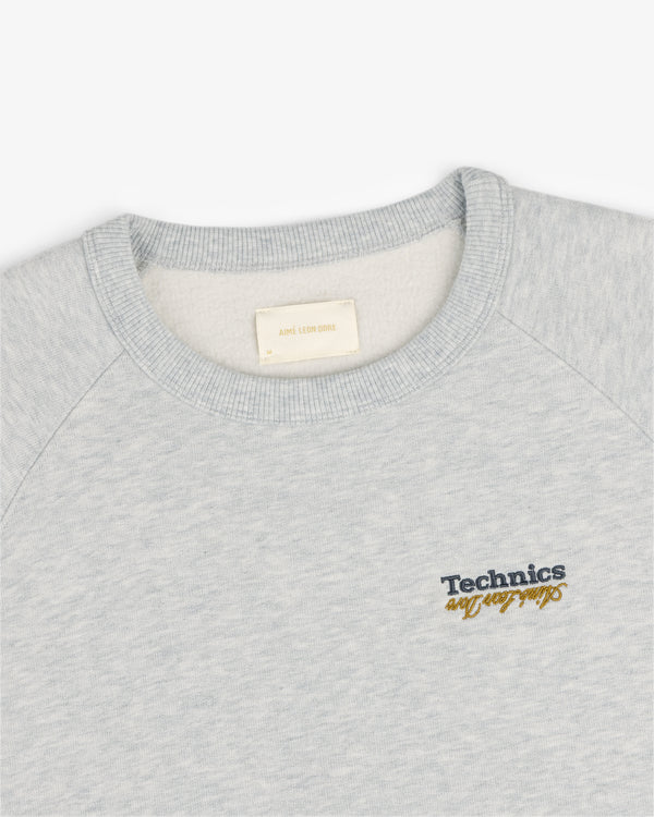 Light gray ALD / Technics World Champions crewneck with yellow script embroidered on the left chest.