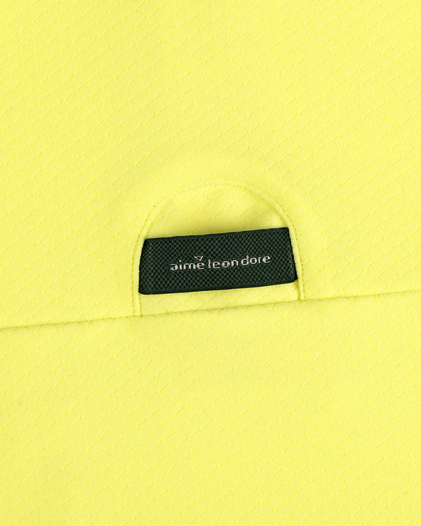 A close-up of an ALD Golf Quarter Zip Pullover’s black Aimé Leon Dore label sewn onto textured yellow fabric.