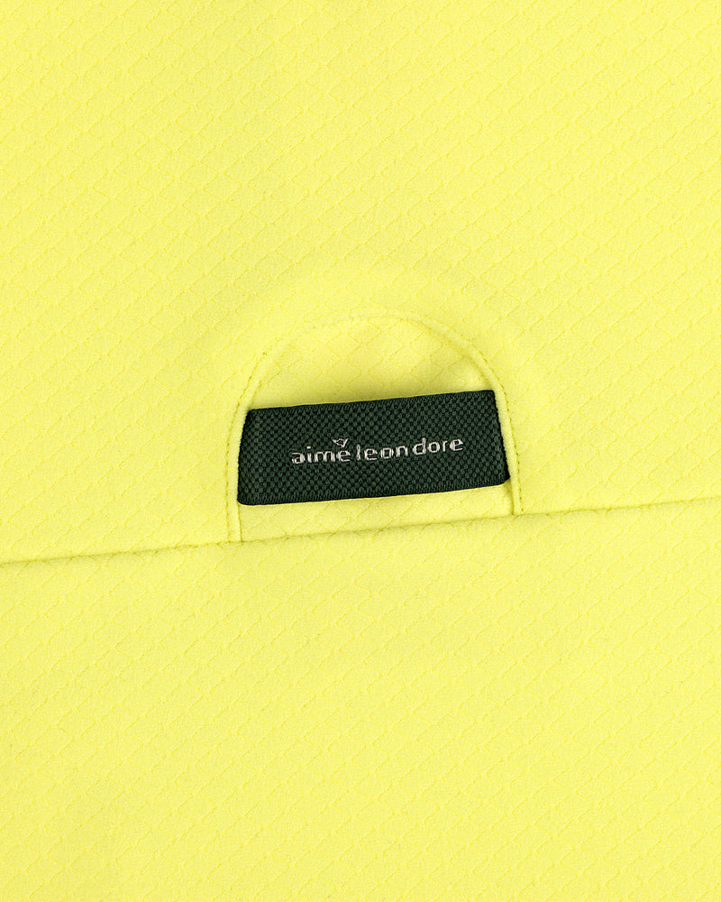 A close-up of an ALD Golf Quarter Zip Pullover’s black Aimé Leon Dore label sewn onto textured yellow fabric.