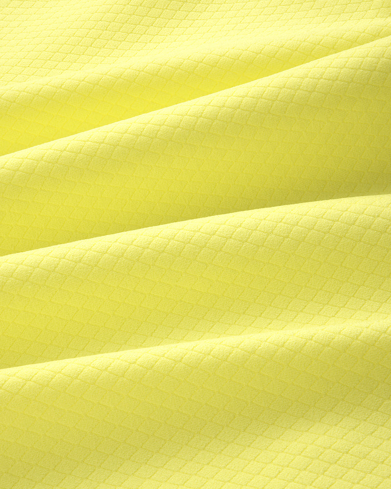 Close-up of the ALD Golf Quarter Zip Pullover's yellow textured fabric with a subtle diamond pattern and soft folds.