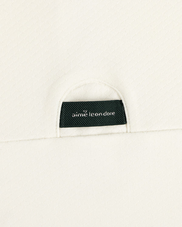 A black Aimé Leon Dore label sewn into the off-white ALD Golf Quarter Zip Pullover’s textured fabric.
