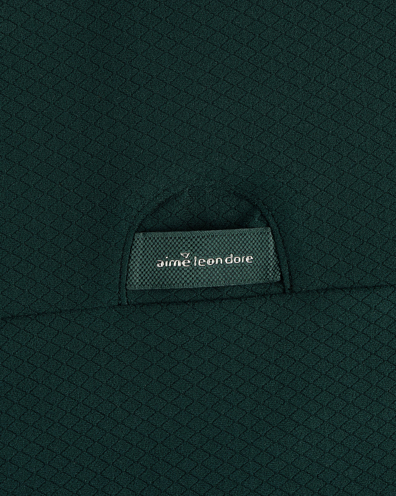 Close-up of textured dark green ALD Golf Quarter Zip Pullover with label partially visible in the pocket.