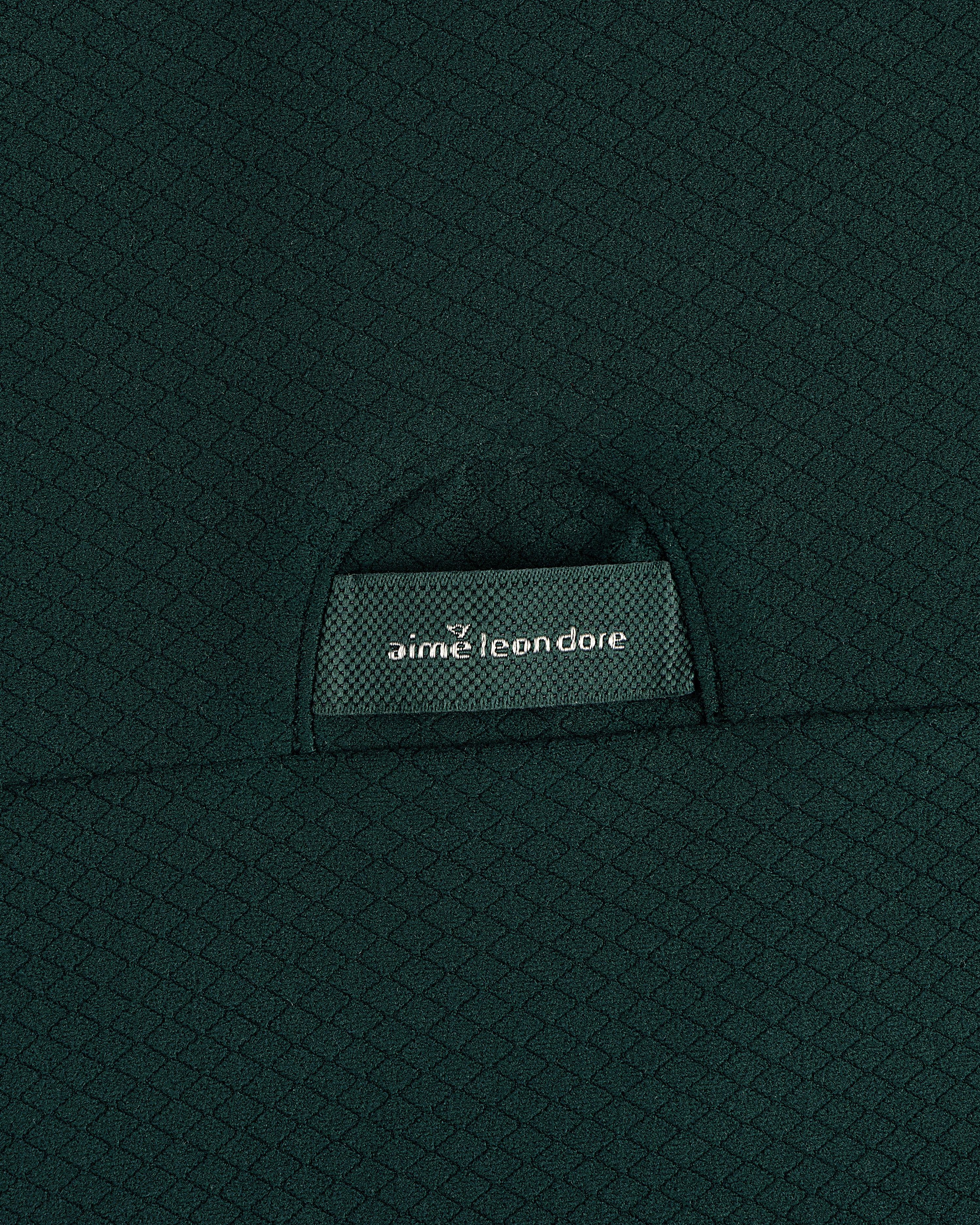 Close-up of textured dark green ALD Golf Quarter Zip Pullover with label partially visible in the pocket.