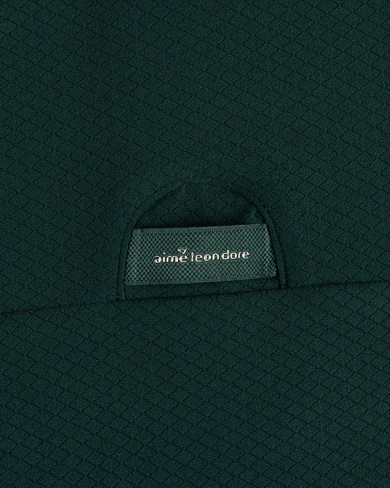 Close-up of textured dark green ALD Golf Quarter Zip Pullover with label partially visible in the pocket.