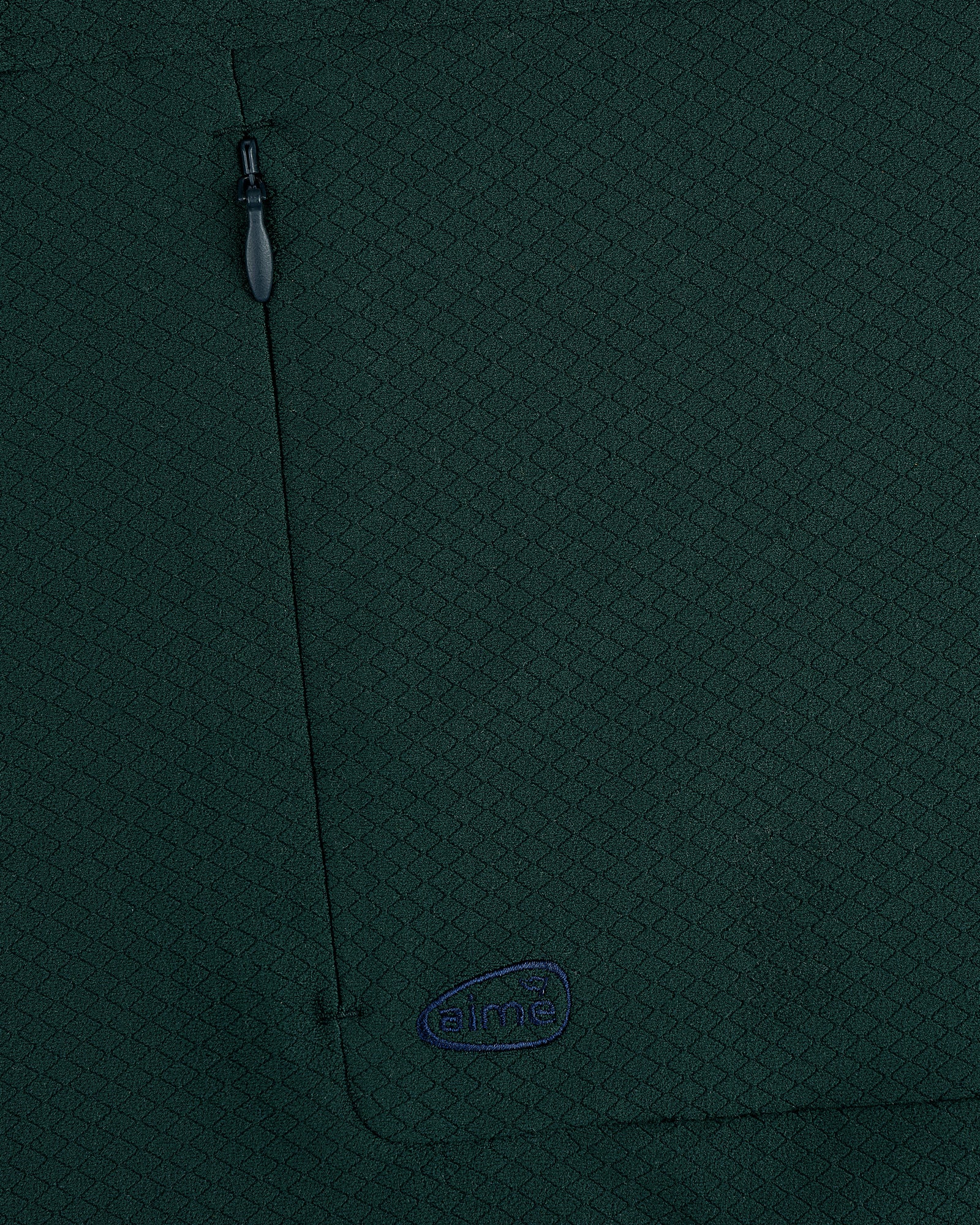 Close-up of ALD Golf Quarter Zip Pullover in dark green with textured fabric, zippered pocket, and small embroidered logo.