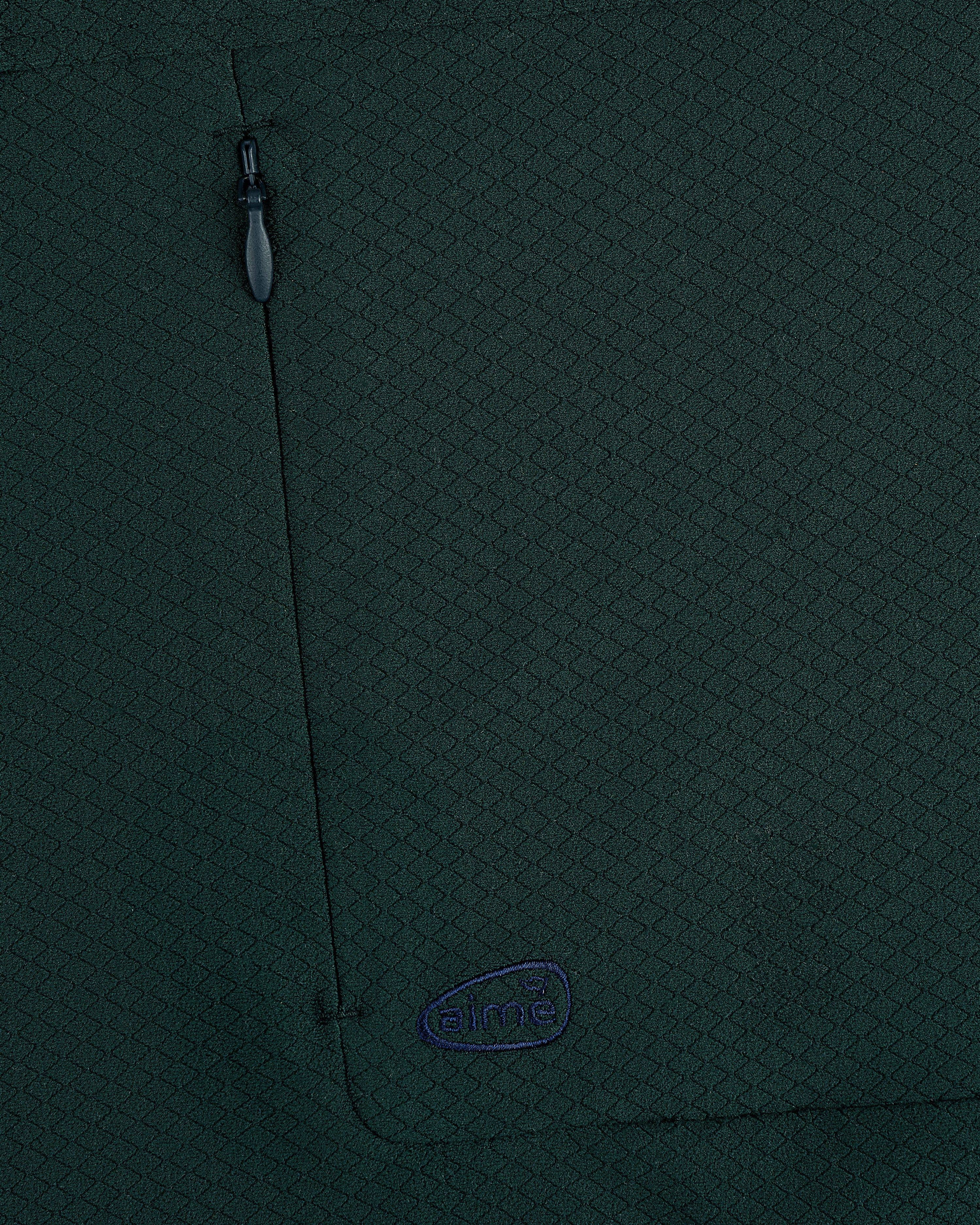 Close-up of ALD Golf Quarter Zip Pullover in dark green with textured fabric, zippered pocket, and small embroidered logo.