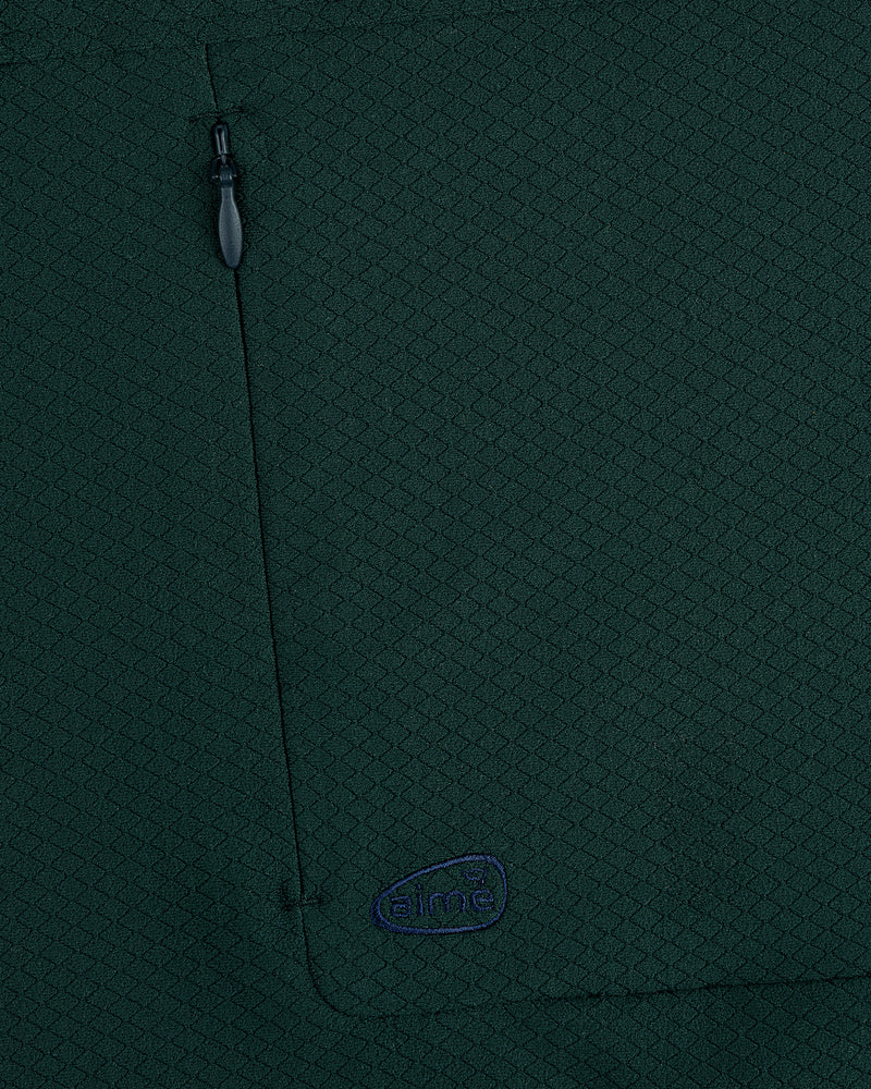 Close-up of ALD Golf Quarter Zip Pullover in dark green with textured fabric, zippered pocket, and small embroidered logo.