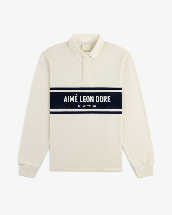 Chest Stripe Logo Rugby: cream long-sleeve polo with black stripe and AIMÉ LEON DORE NEW YORK across chest.
