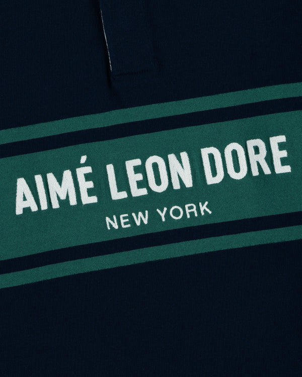 Close-up of the Chest Stripe Logo Rugby with AIMÉ LEON DORE NEW YORK in white on a green stripe.