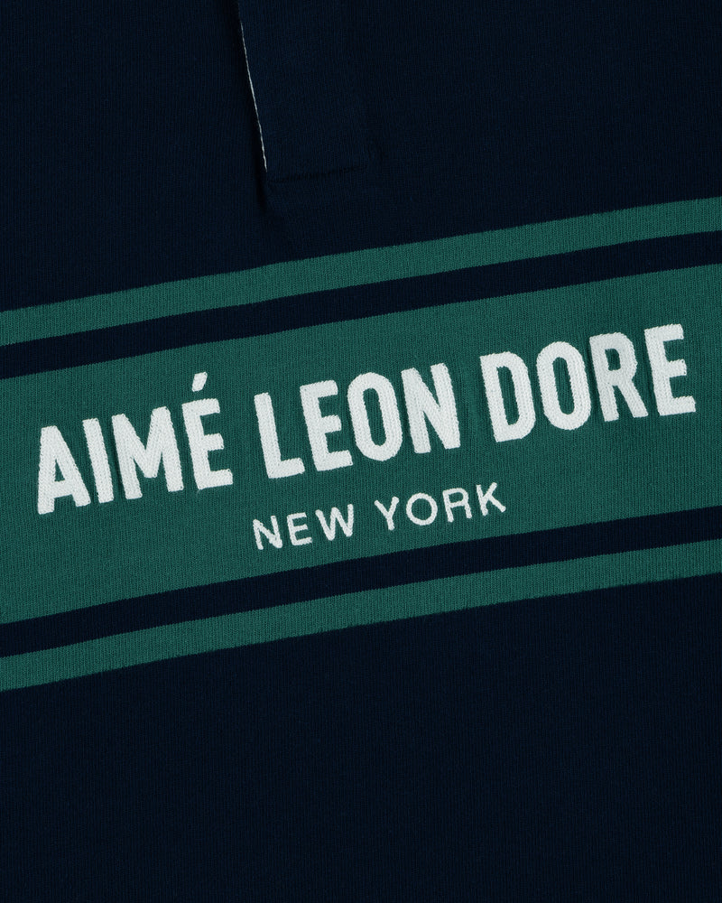 Close-up of the Chest Stripe Logo Rugby with AIMÉ LEON DORE NEW YORK in white on a green stripe.