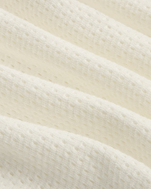 Close-up of soft, white Pointelle Stacked Logo Tee featuring textured fabric with small perforations and gentle folds.