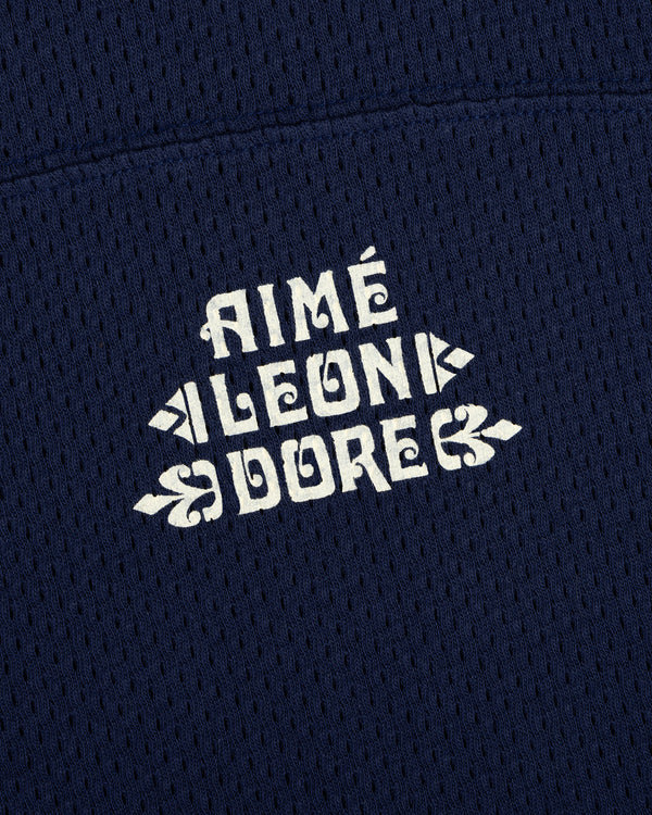 White AIMÉ LEON DORE logo on navy blue mesh fabric of the Pointelle Stacked Logo Tee.