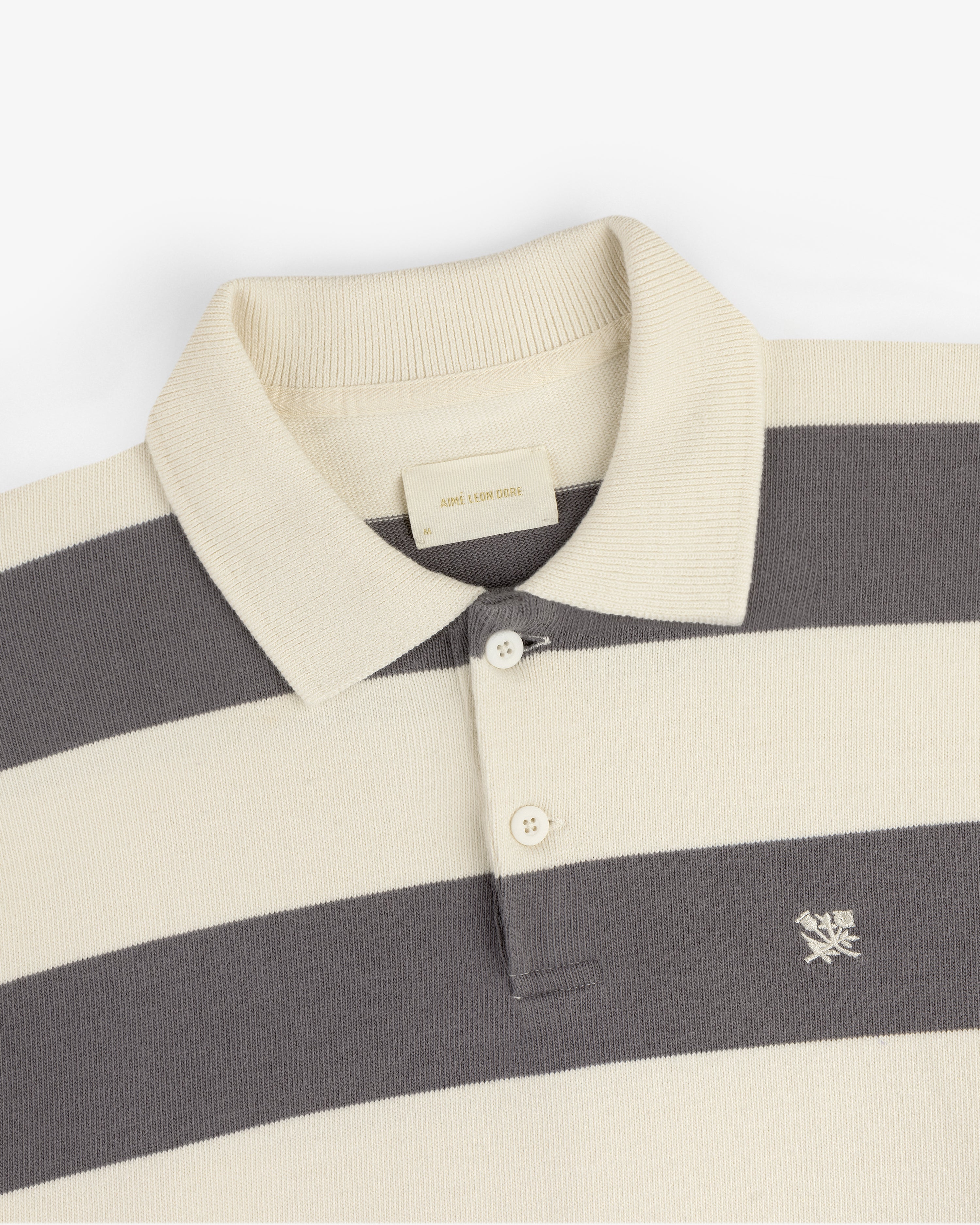 Striped Crest Rugby: cream and gray striped polo with collar, buttons, and small chest embroidered logo.