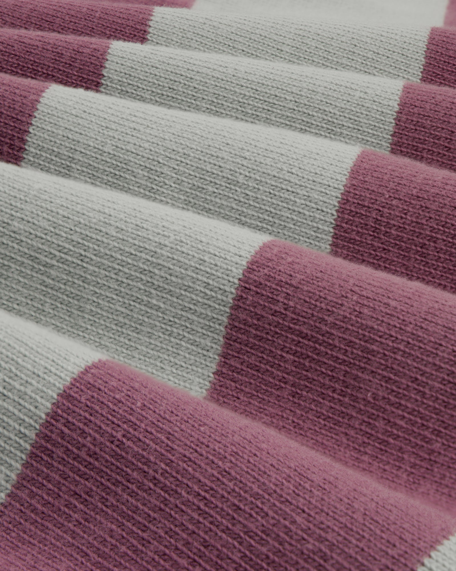 Close-up of the Striped Crest Rugby, featuring wide alternating light gray and mauve knitted stripes.