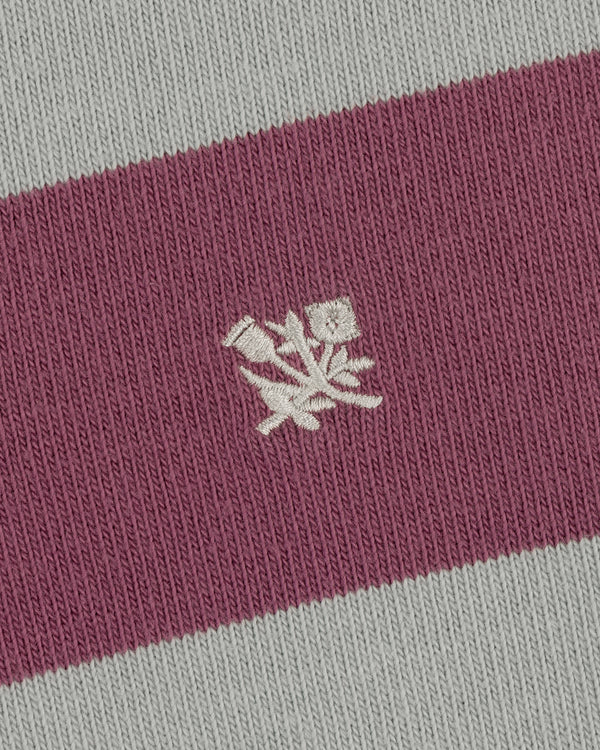 Closeup of the Striped Crest Rugby's pink and gray fabric with a small white embroidered floral design in the center.