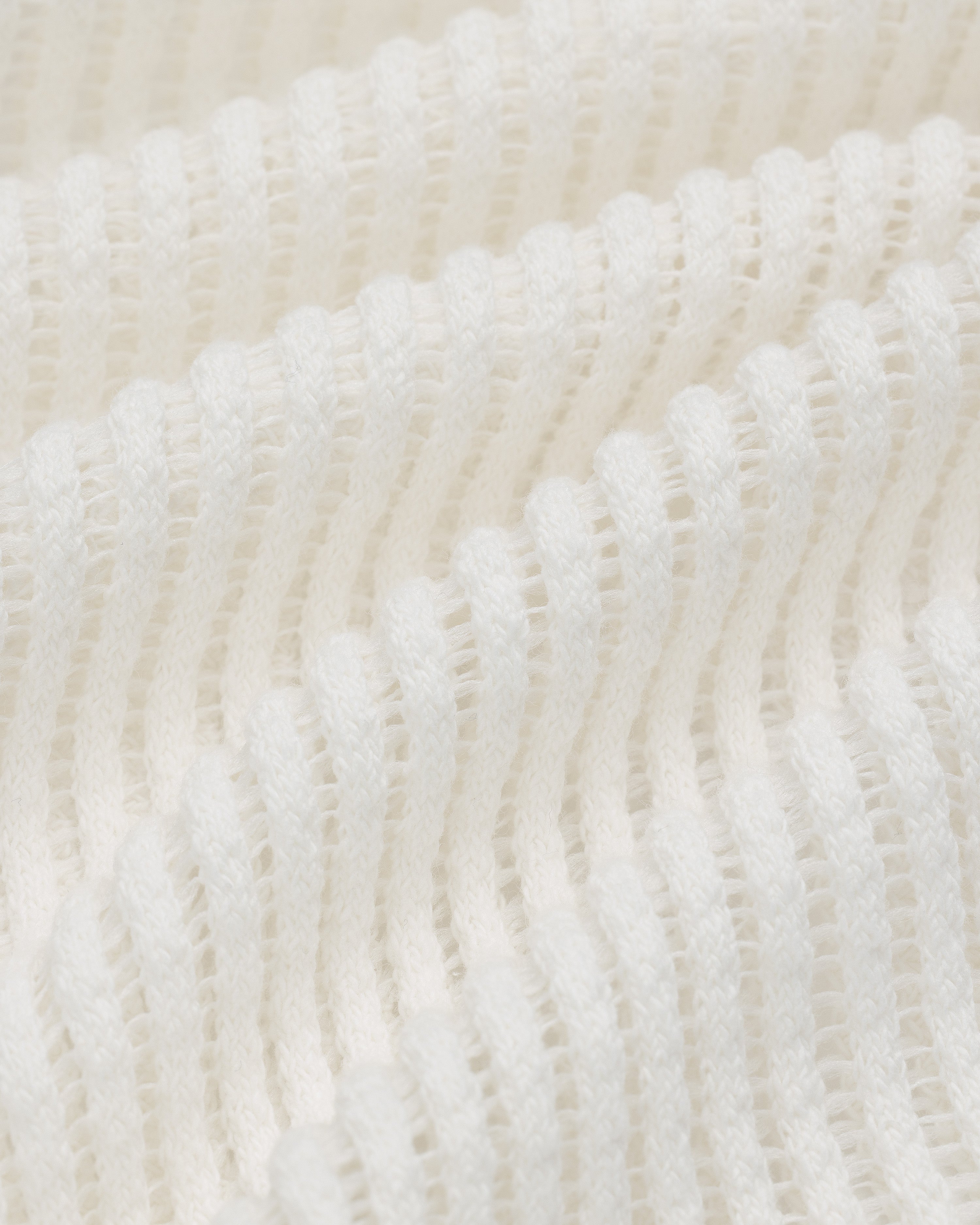 Close-up of Mesh V-Neck Tee in white, featuring ribbed knit texture with wavy horizontal ridges and soft material.
