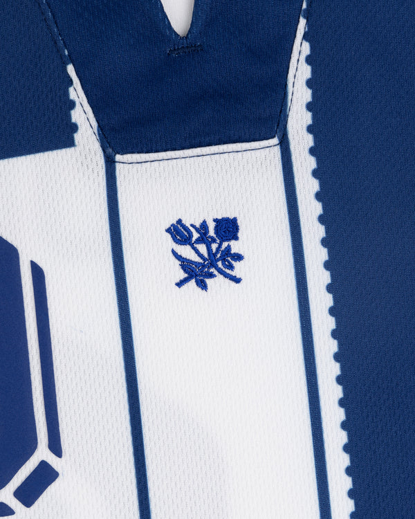 Close-up of the Aimé Cup Soccer Jersey in blue and white, featuring a small embroidered blue rose on the chest.