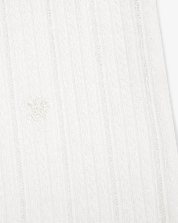 Close-up of the Drop Needle Tank Top's white ribbed fabric with subtle vertical stripes and a central embroidered emblem.